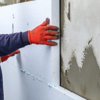 Un homme en train d'isoler un mur par l'extérieur