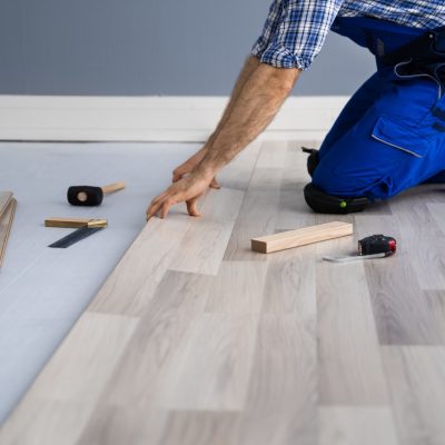 Un homme en tenue de travail, en train de poser du parquet