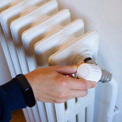 Une main qui règle le robinet thermostatique d'un radiateur