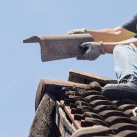 Un homme en train de poser une tuile sur un toit