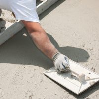 Un ouvrier du bâtiment nivelle du ciment frais une dalle de béton