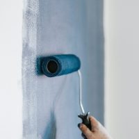 Une main avec un rouleau de peinture en train de peindre un mur